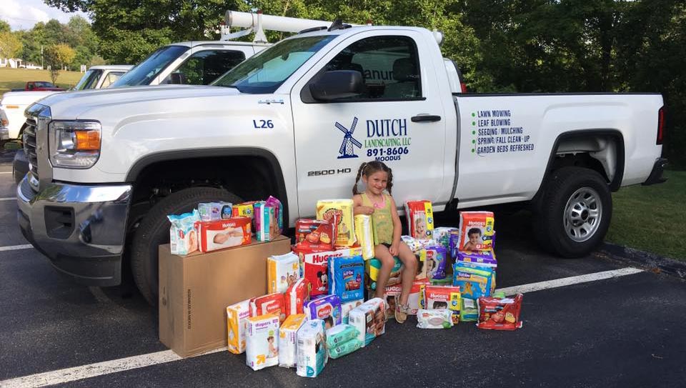 Child sitting in front of Dutch Landscaping truck with community donations